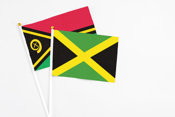 Jamaica and Vanuatu stick flags on white background. High quality fabric, miniature national flag. Peaceful global concept.White floor for copy space.