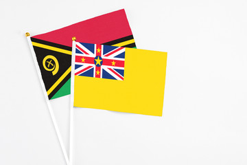 Niue and Vanuatu stick flags on white background. High quality fabric, miniature national flag. Peaceful global concept.White floor for copy space.