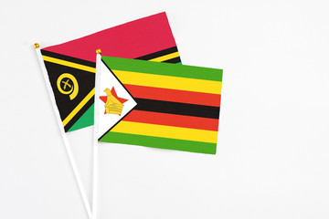 Zimbabwe and Vanuatu stick flags on white background. High quality fabric, miniature national flag. Peaceful global concept.White floor for copy space.