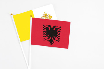 Albania and Vatican City stick flags on white background. High quality fabric, miniature national flag. Peaceful global concept.White floor for copy space.