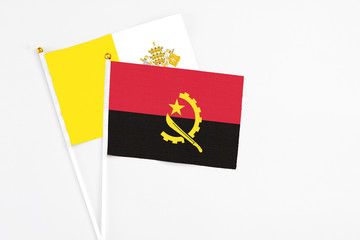 Angola and Vatican City stick flags on white background. High quality fabric, miniature national flag. Peaceful global concept.White floor for copy space.