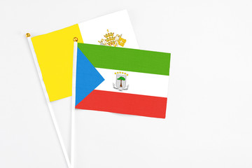 Equatorial Guinea and Vatican City stick flags on white background. High quality fabric, miniature national flag. Peaceful global concept.White floor for copy space.