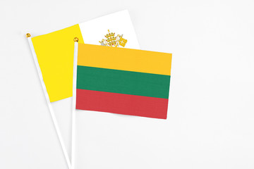 Lithuania and Vatican City stick flags on white background. High quality fabric, miniature national flag. Peaceful global concept.White floor for copy space.