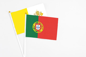 Portugal and Vatican City stick flags on white background. High quality fabric, miniature national flag. Peaceful global concept.White floor for copy space.