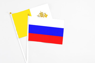 Russia and Vatican City stick flags on white background. High quality fabric, miniature national flag. Peaceful global concept.White floor for copy space.