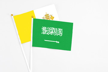 Saudi Arabia and Vatican City stick flags on white background. High quality fabric, miniature national flag. Peaceful global concept.White floor for copy space.