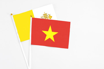 Vietnam and Vatican City stick flags on white background. High quality fabric, miniature national flag. Peaceful global concept.White floor for copy space.