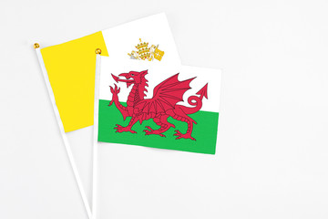 Wales and Vatican City stick flags on white background. High quality fabric, miniature national flag. Peaceful global concept.White floor for copy space.