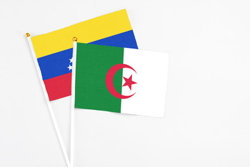 Algeria and Venezuela stick flags on white background. High quality fabric, miniature national flag. Peaceful global concept.White floor for copy space.