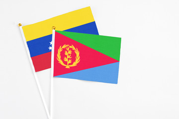 Eritrea and Venezuela stick flags on white background. High quality fabric, miniature national flag. Peaceful global concept.White floor for copy space.