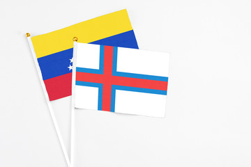 Obraz premium Faroe Islands and Venezuela stick flags on white background. High quality fabric, miniature national flag. Peaceful global concept.White floor for copy space.