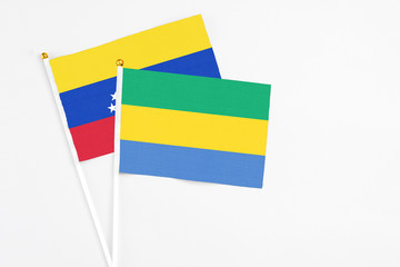 Gabon and Venezuela stick flags on white background. High quality fabric, miniature national flag. Peaceful global concept.White floor for copy space.