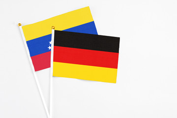 Germany and Venezuela stick flags on white background. High quality fabric, miniature national flag. Peaceful global concept.White floor for copy space.