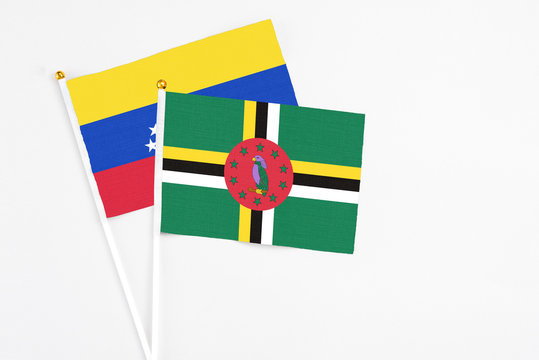 Dominica and Venezuela stick flags on white background. High quality fabric, miniature national flag. Peaceful global concept.White floor for copy space.