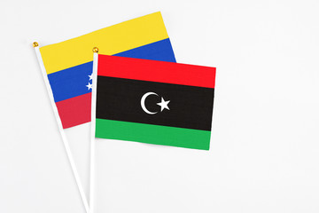 Libya and Venezuela stick flags on white background. High quality fabric, miniature national flag. Peaceful global concept.White floor for copy space.