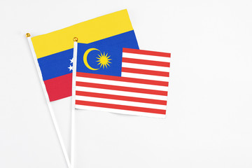 Malaysia and Venezuela stick flags on white background. High quality fabric, miniature national flag. Peaceful global concept.White floor for copy space.