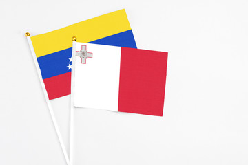 Malta and Venezuela stick flags on white background. High quality fabric, miniature national flag. Peaceful global concept.White floor for copy space.