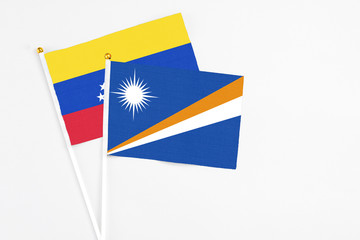 Marshall Islands and Venezuela stick flags on white background. High quality fabric, miniature national flag. Peaceful global concept.White floor for copy space.