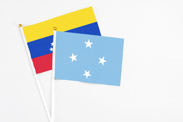 Micronesia and Venezuela stick flags on white background. High quality fabric, miniature national flag. Peaceful global concept.White floor for copy space.