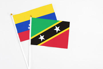 Saint Kitts And Nevis and Venezuela stick flags on white background. High quality fabric, miniature national flag. Peaceful global concept.White floor for copy space.