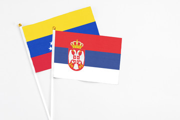 Serbia and Venezuela stick flags on white background. High quality fabric, miniature national flag. Peaceful global concept.White floor for copy space.