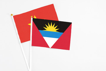 Antigua and Barbuda and Vietnam stick flags on white background. High quality fabric, miniature national flag. Peaceful global concept.White floor for copy space.