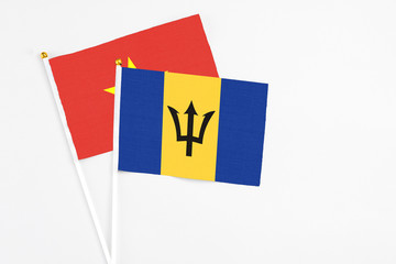 Barbados and Vietnam stick flags on white background. High quality fabric, miniature national flag. Peaceful global concept.White floor for copy space.