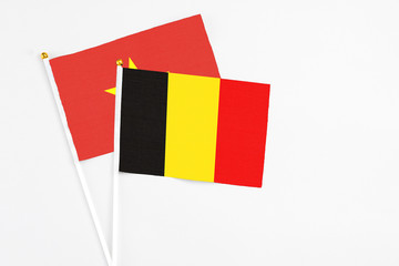Belgium and Vietnam stick flags on white background. High quality fabric, miniature national flag. Peaceful global concept.White floor for copy space.