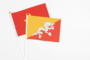 Bhutan and Vietnam stick flags on white background. High quality fabric, miniature national flag. Peaceful global concept.White floor for copy space.