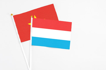 Luxembourg and Vietnam stick flags on white background. High quality fabric, miniature national flag. Peaceful global concept.White floor for copy space.