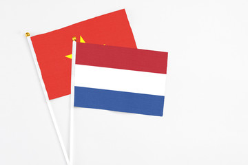 Netherlands and Vietnam stick flags on white background. High quality fabric, miniature national flag. Peaceful global concept.White floor for copy space.