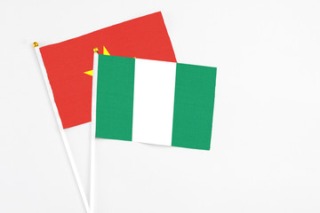 Fototapeta premium Nigeria and Vietnam stick flags on white background. High quality fabric, miniature national flag. Peaceful global concept.White floor for copy space.