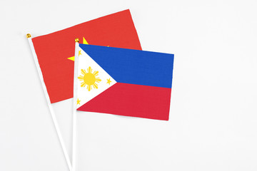 Philippines and Vietnam stick flags on white background. High quality fabric, miniature national flag. Peaceful global concept.White floor for copy space.