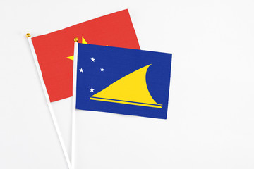 Tokelau and Vietnam stick flags on white background. High quality fabric, miniature national flag. Peaceful global concept.White floor for copy space.