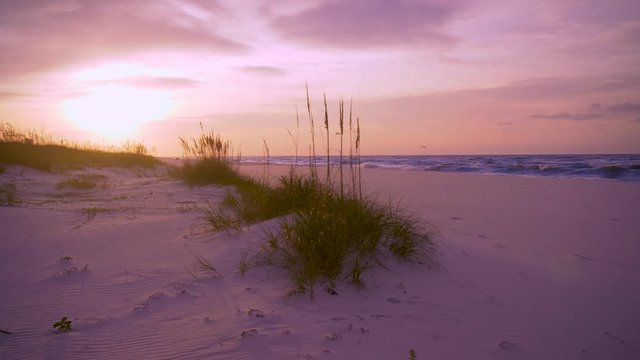 The sun glows in this amazing beach scene from Gulf shores Alabama; the sunglow and saltwater haze creates a soft ethereal feel to this magical moment where the ocean kisses the sand at sunrise.  