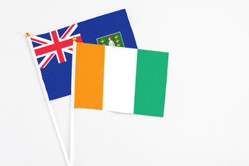 Cote D'Ivoire and British Virgin Islands stick flags on white background. High quality fabric, miniature national flag. Peaceful global concept.White floor for copy space.