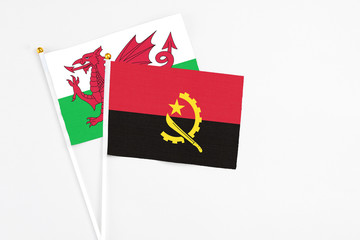 Angola and Wales stick flags on white background. High quality fabric, miniature national flag. Peaceful global concept.White floor for copy space.