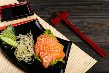 Fresh salmon fish at restaurant very delicious. Japanese foods sashimi on black wood background.