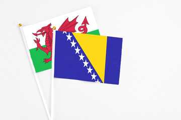Bosnia Herzegovina and Wales stick flags on white background. High quality fabric, miniature national flag. Peaceful global concept.White floor for copy space.