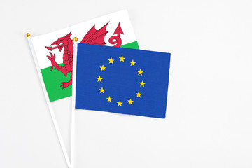 European Union and Wales stick flags on white background. High quality fabric, miniature national flag. Peaceful global concept.White floor for copy space.
