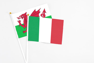 Italy and Wales stick flags on white background. High quality fabric, miniature national flag. Peaceful global concept.White floor for copy space.