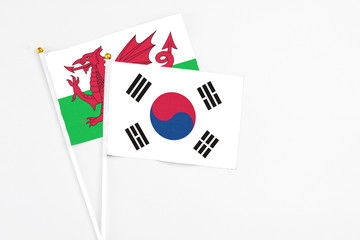 South Korea and Wales stick flags on white background. High quality fabric, miniature national flag. Peaceful global concept.White floor for copy space.