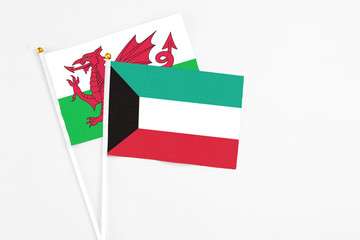 Kuwait and Wales stick flags on white background. High quality fabric, miniature national flag. Peaceful global concept.White floor for copy space.