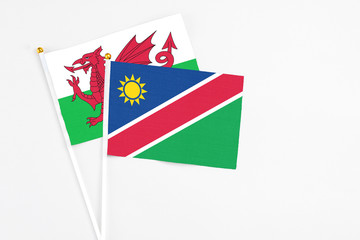 Namibia and Wales stick flags on white background. High quality fabric, miniature national flag. Peaceful global concept.White floor for copy space.