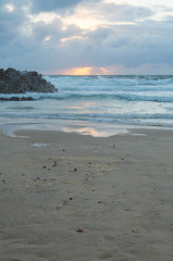 Sun rising over the horizon at a beach by a headland