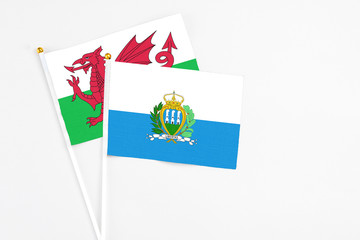 San Marino and Wales stick flags on white background. High quality fabric, miniature national flag. Peaceful global concept.White floor for copy space.