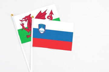 Slovenia and Wales stick flags on white background. High quality fabric, miniature national flag. Peaceful global concept.White floor for copy space.