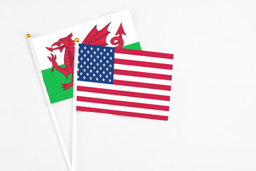 Fototapeta na wymiar United States and Wales stick flags on white background. High quality fabric, miniature national flag. Peaceful global concept.White floor for copy space.