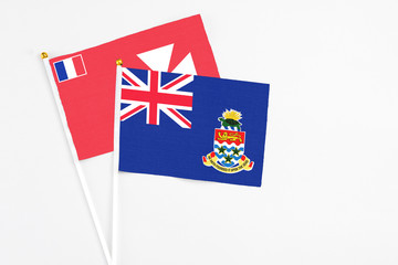 Fototapeta premium Cayman Islands and Wallis And Futuna stick flags on white background. High quality fabric, miniature national flag. Peaceful global concept.White floor for copy space.