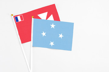 Micronesia and Wallis And Futuna stick flags on white background. High quality fabric, miniature national flag. Peaceful global concept.White floor for copy space.